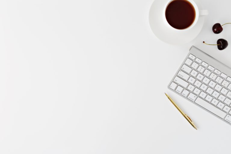 Apple keyboard, pen, coffee on a white background. Image by Leone Venter
